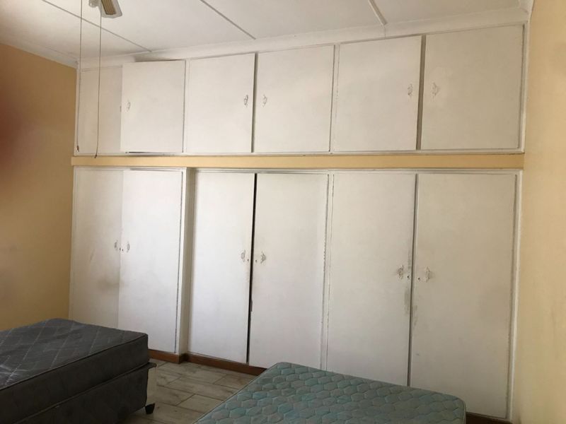 Bedroom featuring extensive floor-to-ceiling built-in cupboards and tiled flooring, offering ample storage space.