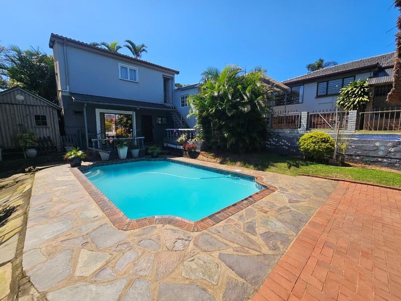 Outdoor pool area featuring a swimming pool surrounded by stone and brick paving, with an external staircase and multi-level garden landscaping.
