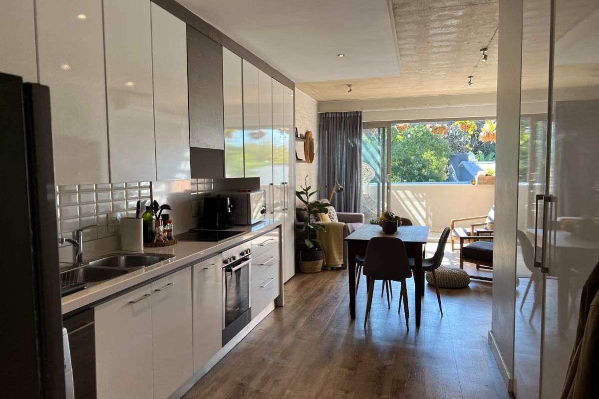 Modern open-plan kitchen and dining area featuring sleek cabinetry, integrated appliances, and direct access to a private balcony through sliding glass doors.