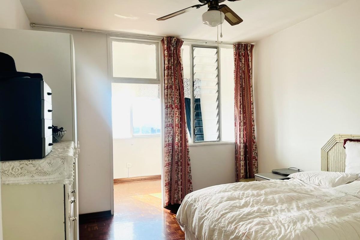 A bedroom featuring parquet flooring, a ceiling fan, and louver windows with direct access to an adjoining balcony area.
