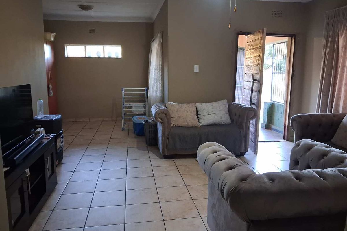 A spacious living room featuring neutral wall tones, tiled flooring, and direct access to an outdoor patio area.