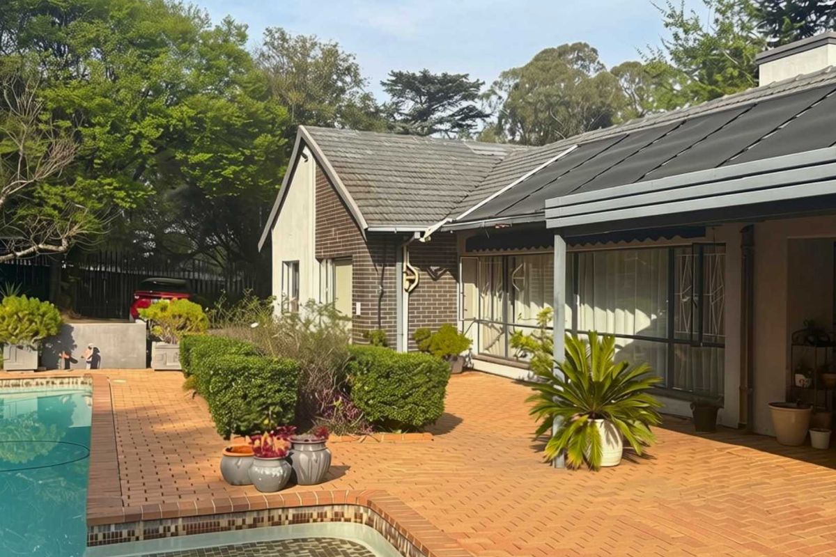 Rear exterior view featuring a brick-paved patio area, a swimming pool, and a well-maintained garden setting with a tiled roof structure.