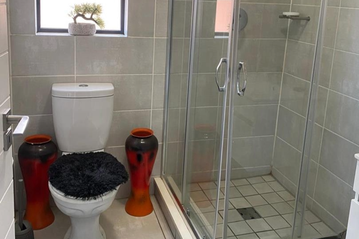 A functional bathroom featuring a glass-enclosed shower, tiled walls, and a standard toilet.
