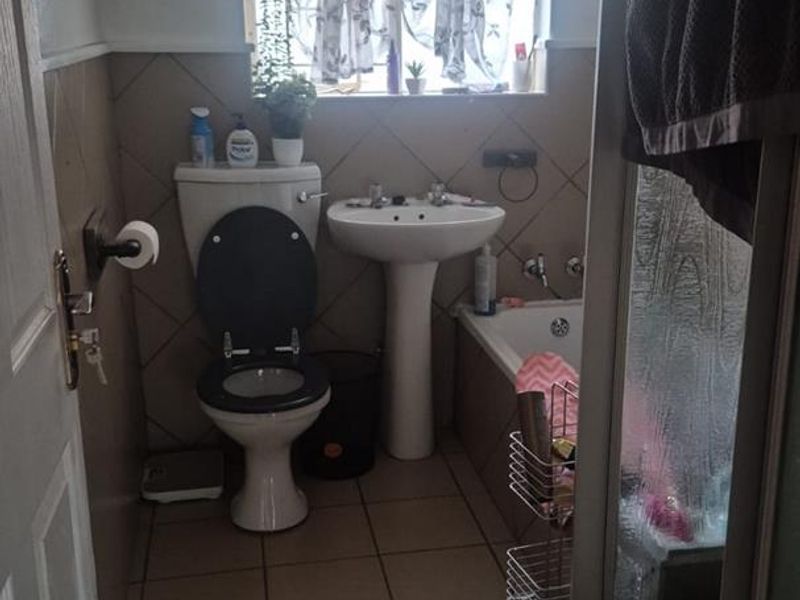 A compact bathroom featuring a pedestal basin, toilet, bathtub, and separate shower enclosure with tiled finishes throughout.