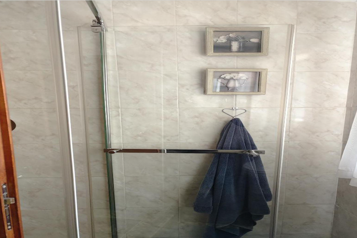 A functional bathroom shower enclosure featuring glass paneling and neutral wall tiling.