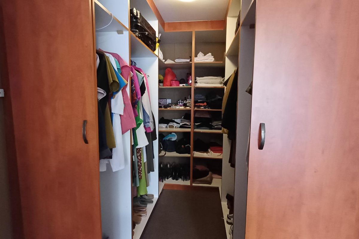 A walk-in closet featuring extensive built-in wooden cabinetry with integrated shelving and hanging rails for organized storage.