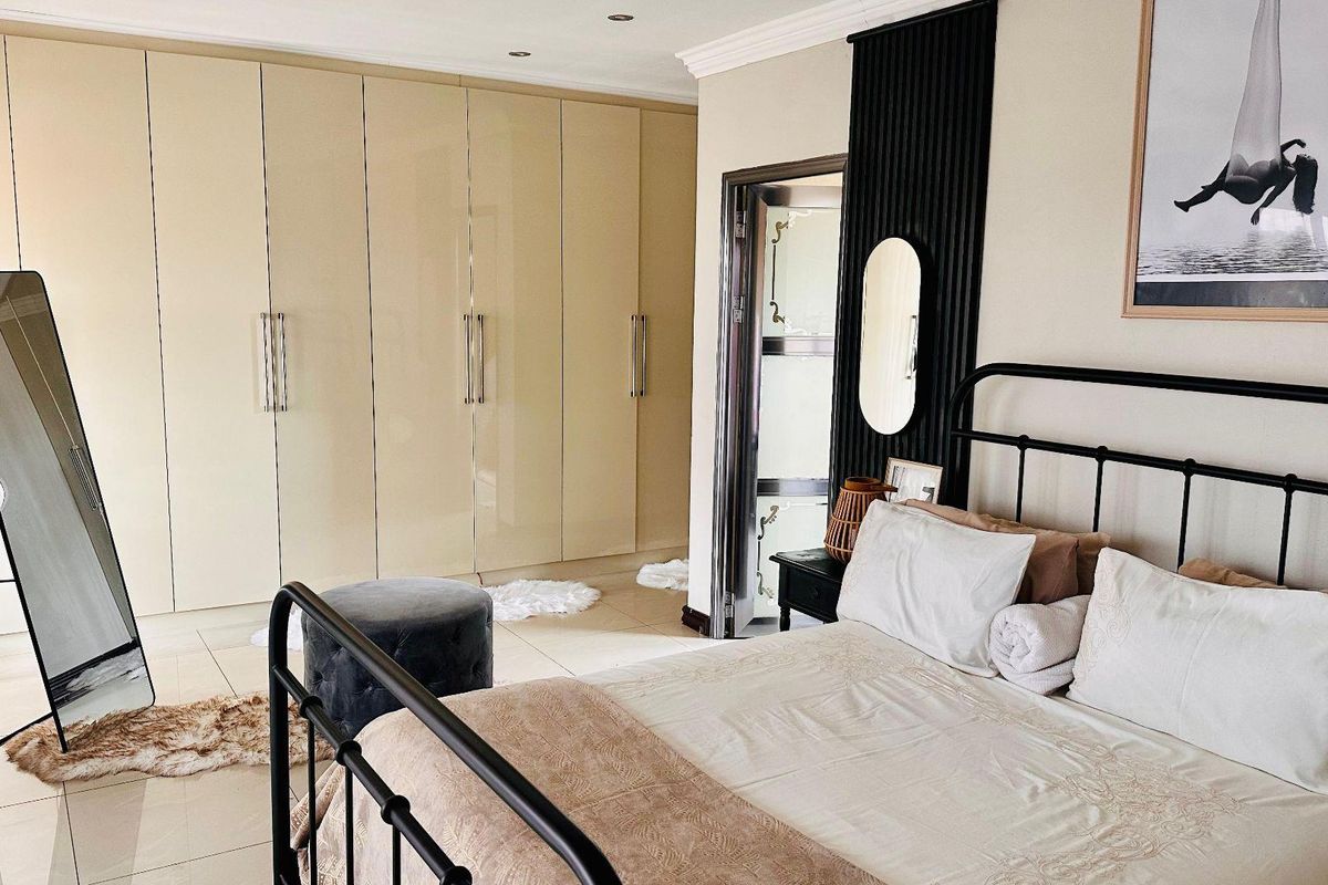 A well-maintained bedroom featuring extensive floor-to-ceiling built-in cabinetry, tiled flooring, and a decorative black slatted wall feature.