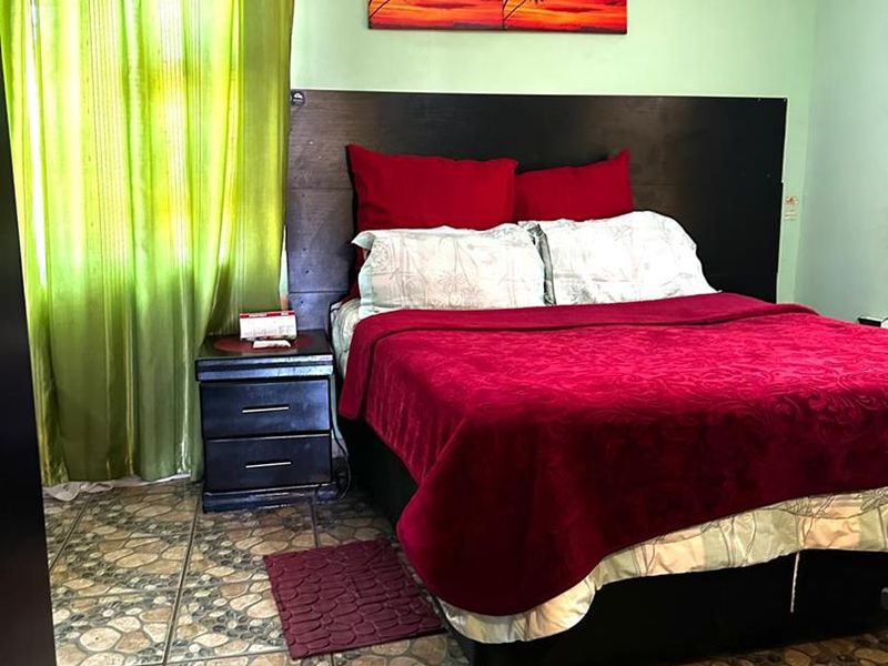 A bedroom featuring tiled flooring, crown molding, and a wall-mounted air conditioning unit.