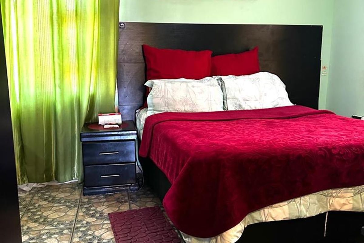 A bedroom featuring tiled flooring, crown molding, and a wall-mounted air conditioning unit.