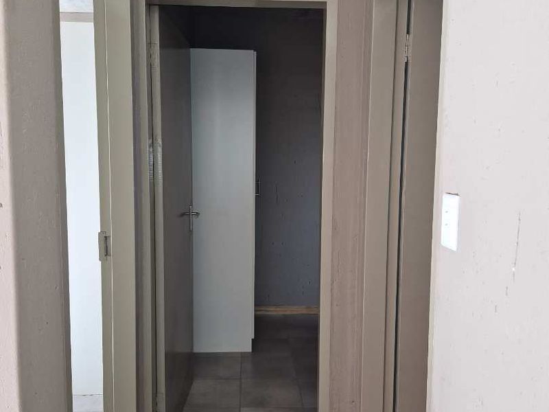 A functional hallway featuring tiled flooring and multiple internal doorways, currently requiring cosmetic updates to the walls and ceiling finishes.