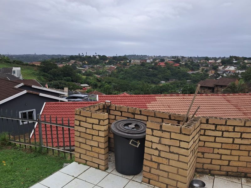 Elevated view overlooking the surrounding residential neighborhood, featuring a brick-walled patio area and tiled roofing.