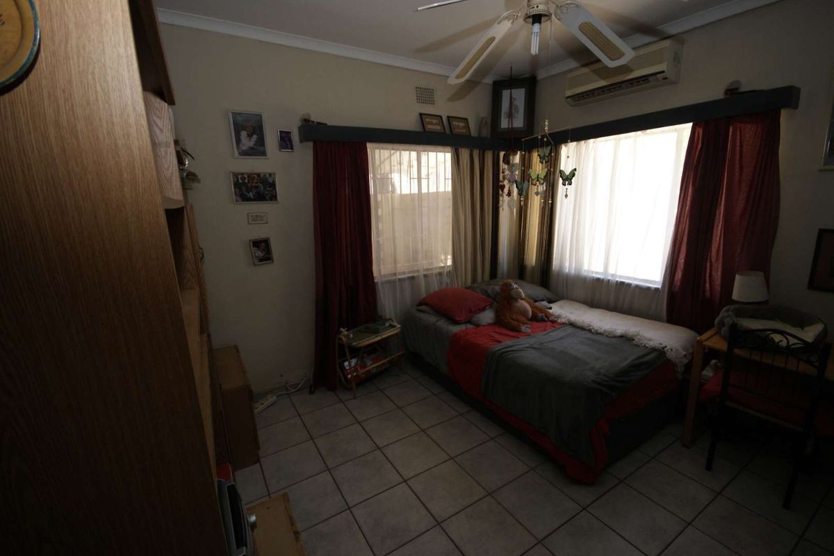 A bedroom featuring tiled flooring, a ceiling fan, and a wall-mounted air conditioning unit.