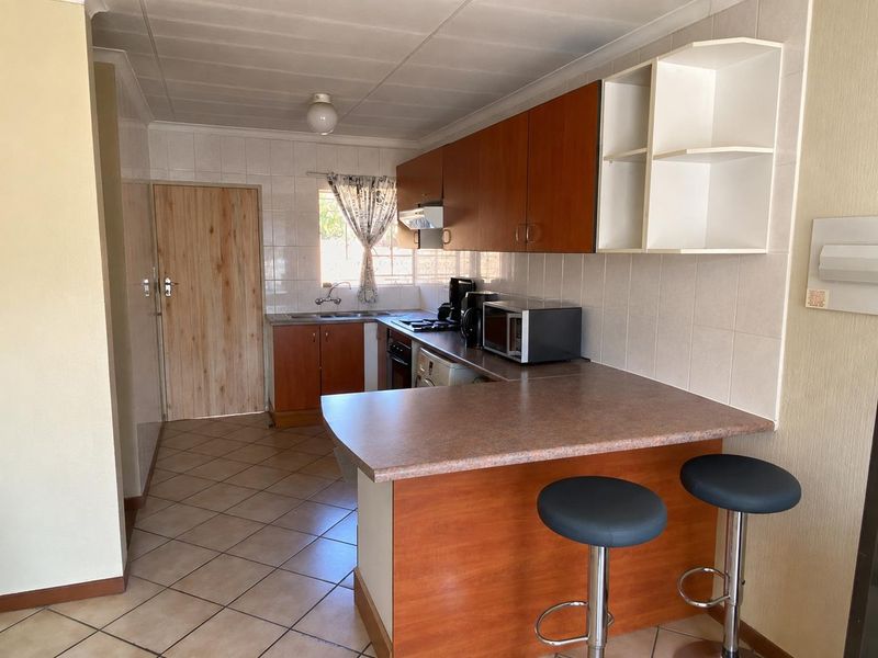 Functional kitchen featuring laminate cabinetry, a breakfast bar, tiled backsplash, and ceramic flooring, offering a practical layout for daily meal preparation.