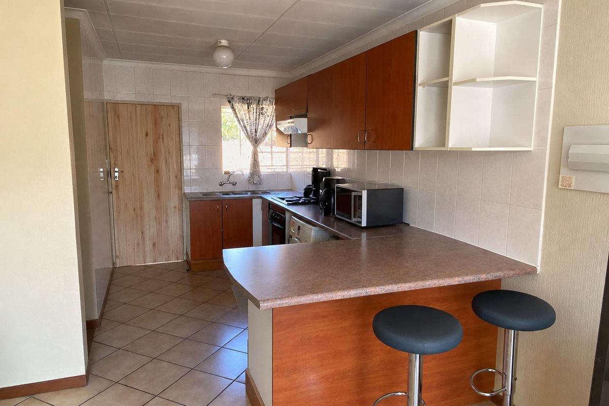 Functional kitchen featuring laminate cabinetry, a breakfast bar, tiled backsplash, and ceramic flooring, offering a practical layout for daily meal preparation.