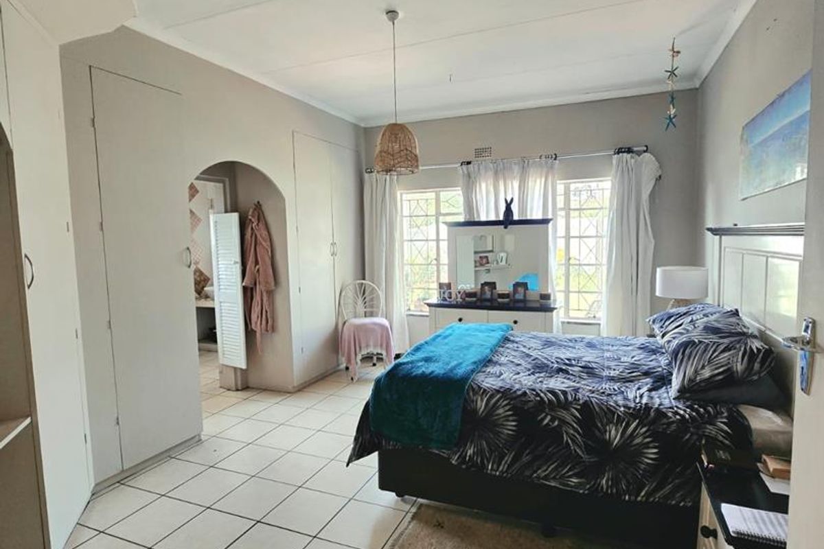 Spacious bedroom featuring built-in cupboards, tiled flooring, and an arched entryway leading to an adjacent space.