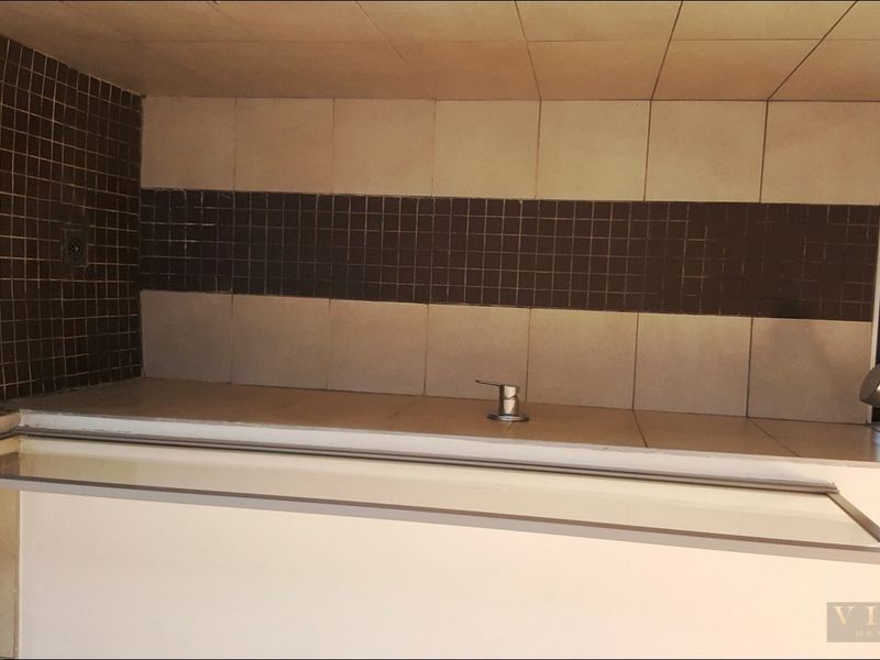 A dated bathroom shower area featuring tiled walls and a basic shower fixture, currently requiring renovation to update the finishes and fixtures.