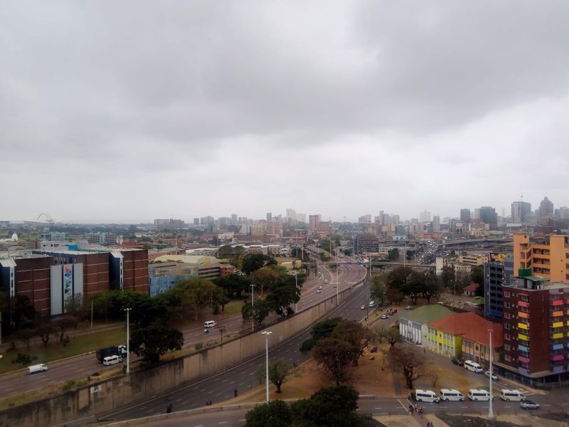 Elevated urban cityscape view overlooking major roads, surrounding buildings, and infrastructure under an overcast sky.