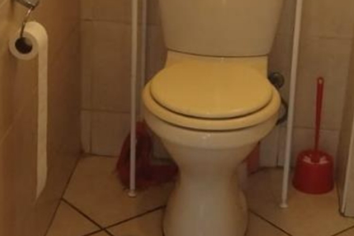 A compact bathroom featuring a standard toilet and tiled flooring and walls.