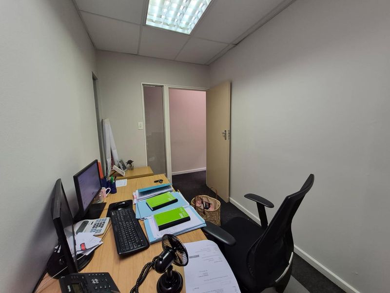 A functional office space featuring a suspended ceiling with integrated lighting and a glass panel door, providing a professional work environment.