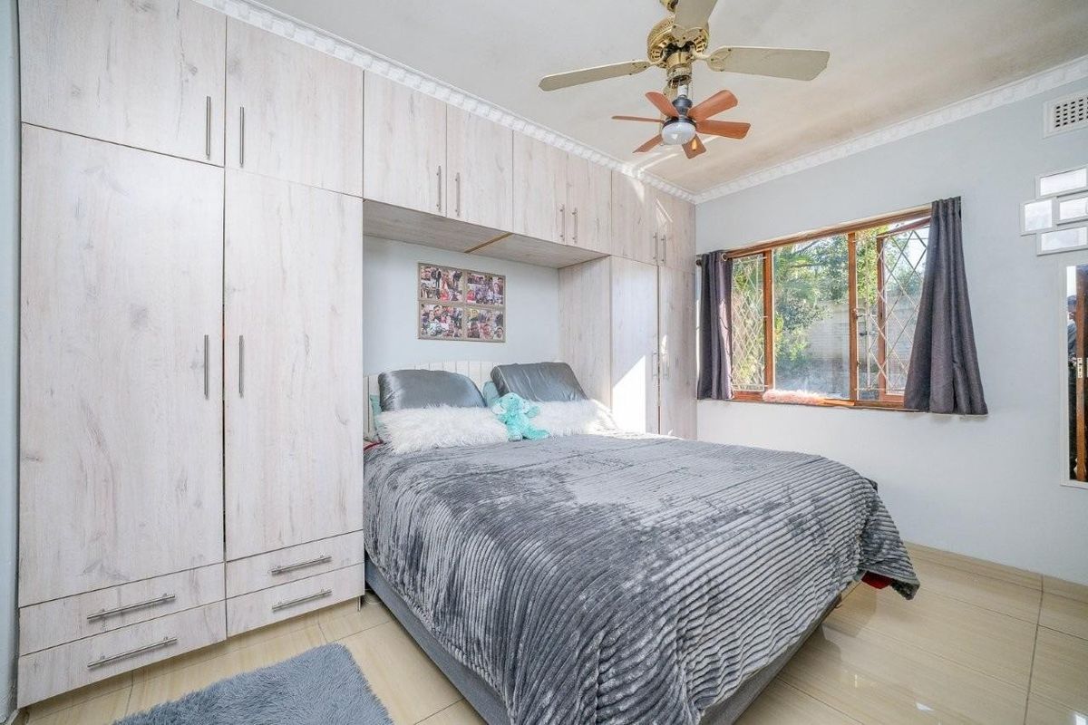 A bedroom featuring extensive built-in cabinetry, tiled flooring, a ceiling fan, and security bars on the window.