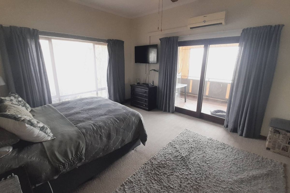 Spacious bedroom featuring carpeted flooring, a wall-mounted air conditioning unit, and sliding glass doors providing access to an outdoor balcony area.