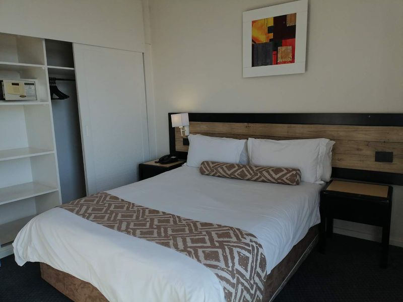 A bedroom featuring a built-in wardrobe with shelving and a wall-mounted headboard with integrated lighting.