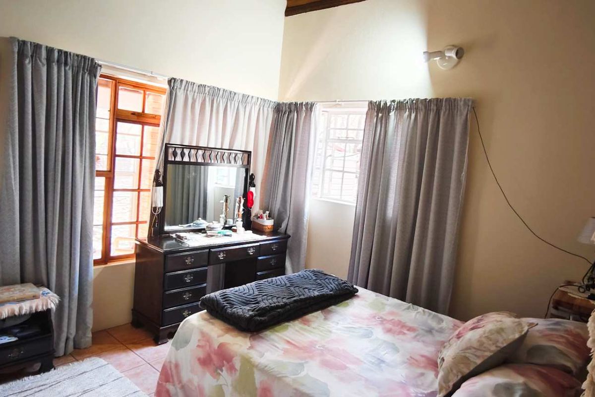A bedroom featuring tiled flooring, large windows with curtains, and high ceilings, providing a functional and comfortable living space.