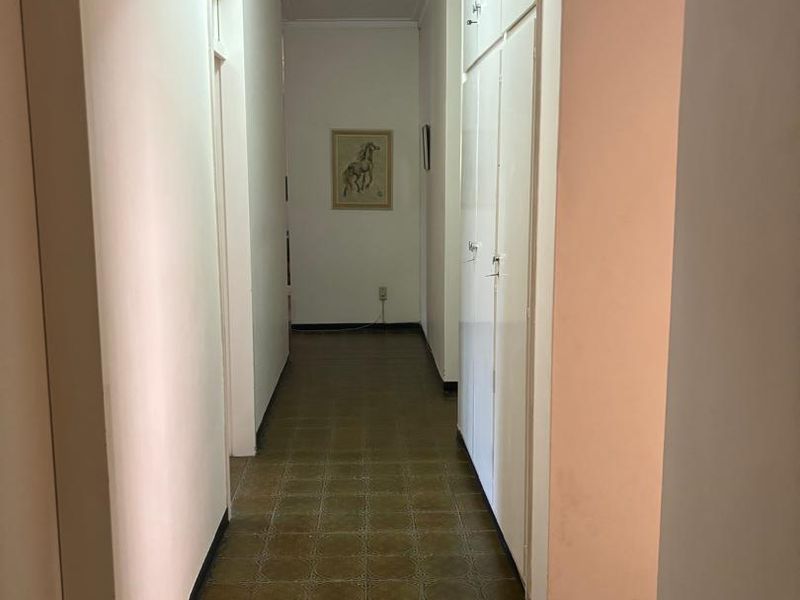 A functional hallway featuring built-in storage cupboards and patterned tile flooring, providing access to various rooms within the home.