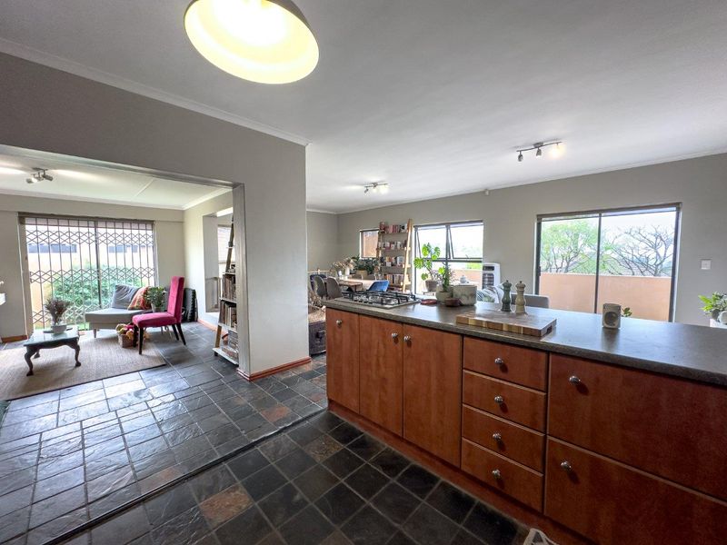 Spacious open-plan living area featuring a kitchen island with gas hob, slate tile flooring, and large sliding doors leading to an outdoor space.