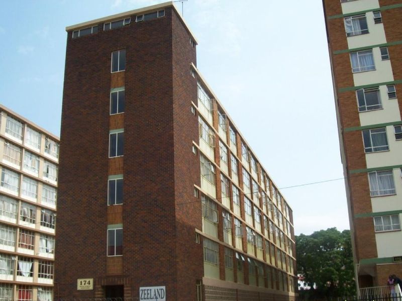 Exterior view of a multi-story brick apartment building featuring a prominent facade and multiple window units.