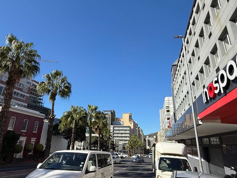 A street-level view of a commercial office building in an urban setting, featuring prominent signage and surrounding city infrastructure.