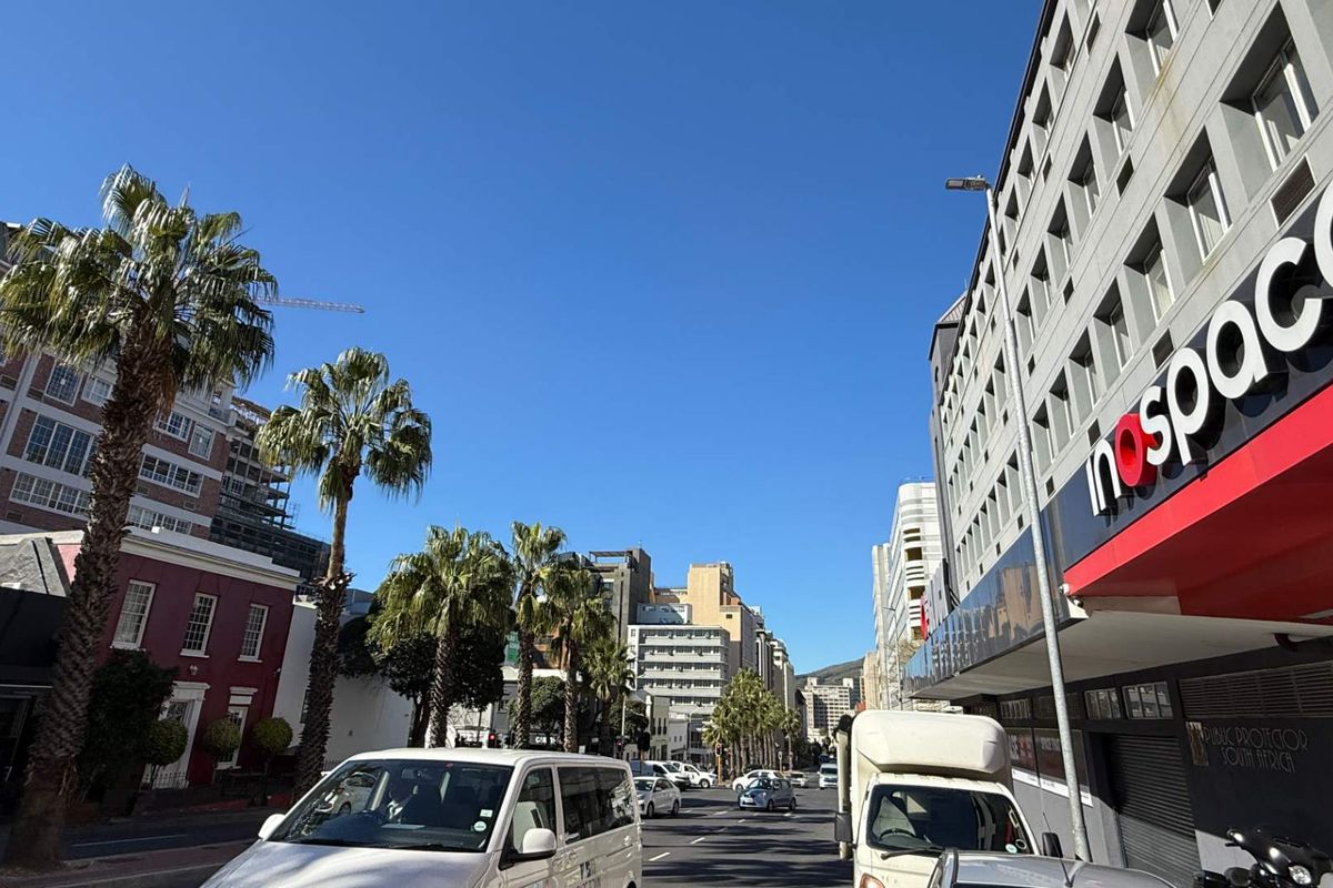A street-level view of a commercial office building in an urban setting, featuring prominent signage and surrounding city infrastructure.