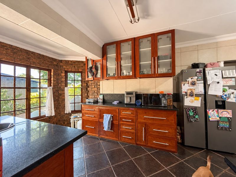 A well-maintained kitchen featuring warm wooden cabinetry, granite countertops, and a distinctive exposed brick wall, offering a classic and functional cooking space.