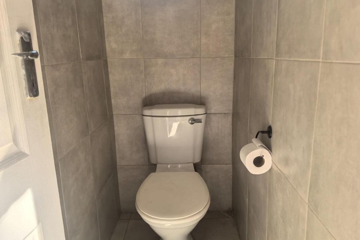 A compact, tiled guest toilet featuring neutral ceramic wall and floor tiles.