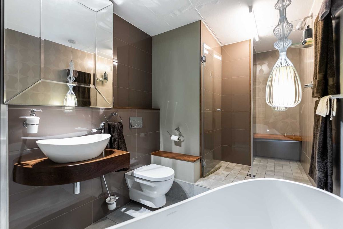 Modern bathroom featuring a vessel sink on a floating vanity, wall-hung toilet, glass-enclosed walk-in shower, and a sleek freestanding bathtub with contemporary tiled finishes.