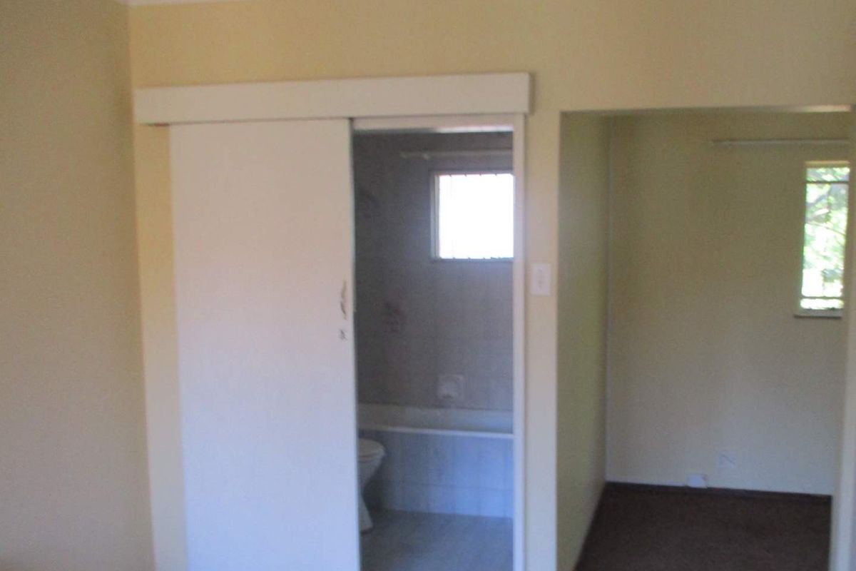 A bedroom featuring a sliding door leading to an en-suite bathroom, with neutral wall finishes and carpeted flooring.