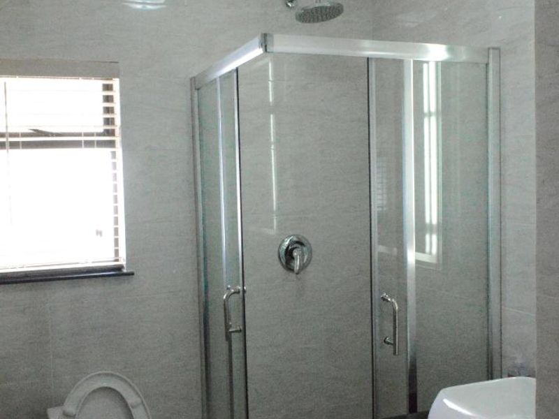 A clean, modern bathroom featuring a glass-enclosed shower, a vanity with a basin, and neutral wall and floor tiling.