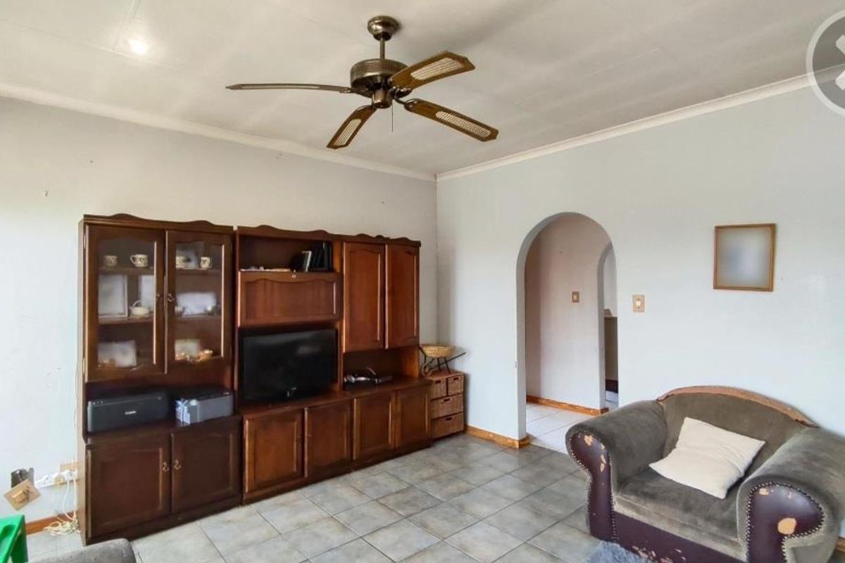 A living room featuring tiled flooring, a ceiling fan, and an arched doorway leading to an adjacent space.
