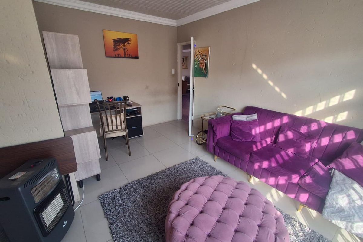 A living room featuring tiled flooring, a tongue-and-groove ceiling, and a doorway leading to an adjacent room.