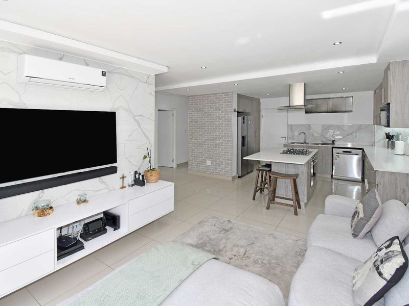 Modern open-plan living area featuring a marble-look feature wall, split-system air conditioning, and a contemporary kitchen with stone countertops and a central island.