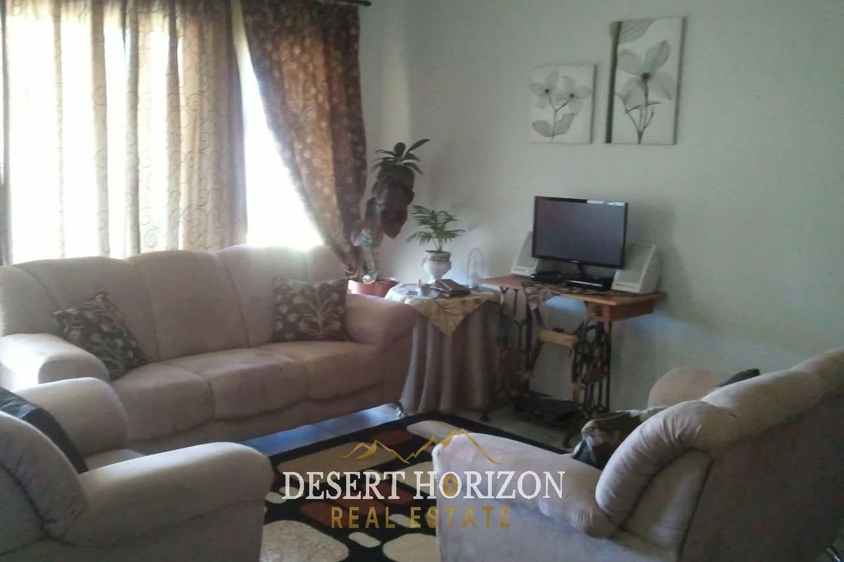 A standard living room area featuring neutral wall finishes and window treatments, providing a functional space for relaxation.