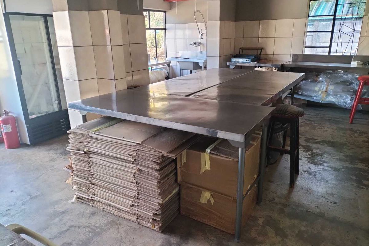 A functional commercial-style kitchen or utility space featuring stainless steel prep tables, tiled walls, and a dedicated wash-up area.