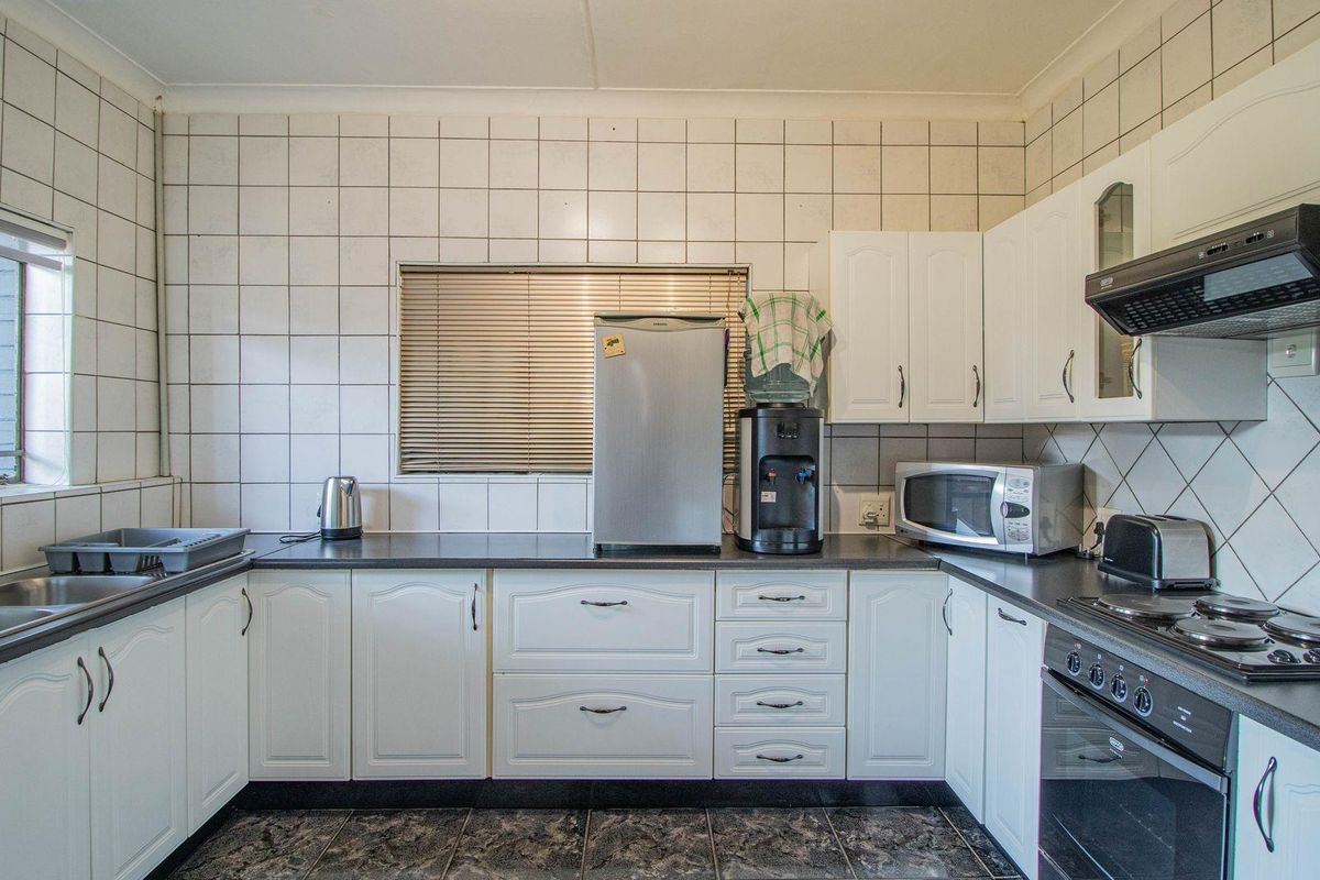 A functional kitchen featuring white cabinetry, dark countertops, a built-in oven with extractor fan, and tiled wall splashbacks.
