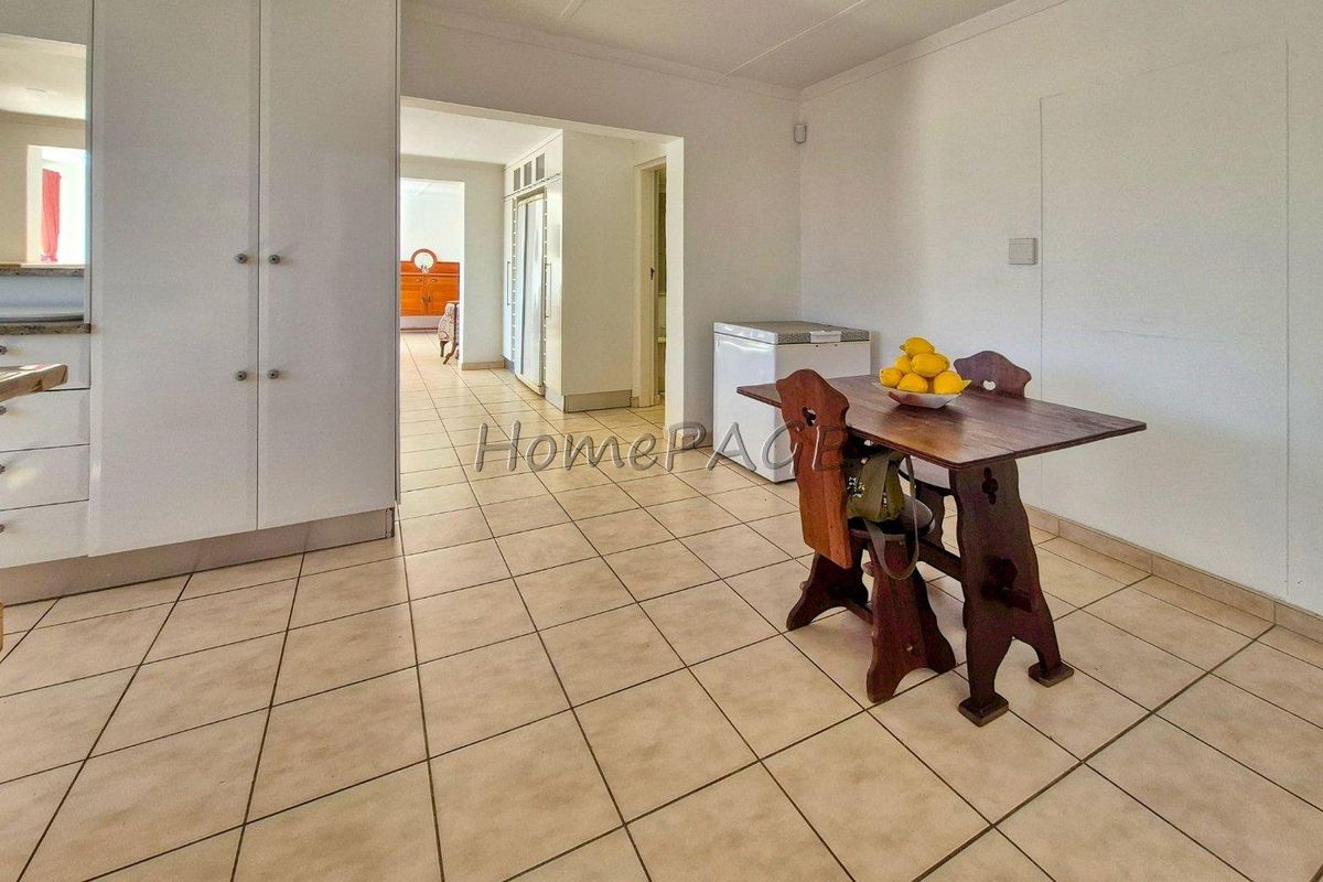 A functional kitchen and dining area featuring tiled flooring, built-in white cabinetry, and a clear transition into the adjacent hallway.