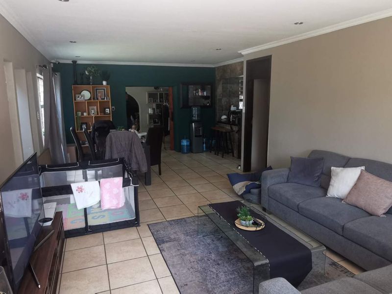 Spacious open-plan living area featuring tiled flooring, recessed lighting, and a decorative stone-cladding feature wall, providing a versatile layout for dining and relaxation.