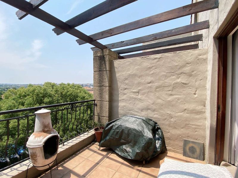 A private balcony featuring a timber pergola, wrought iron balustrade, and tiled flooring, offering an elevated outdoor space with scenic views.