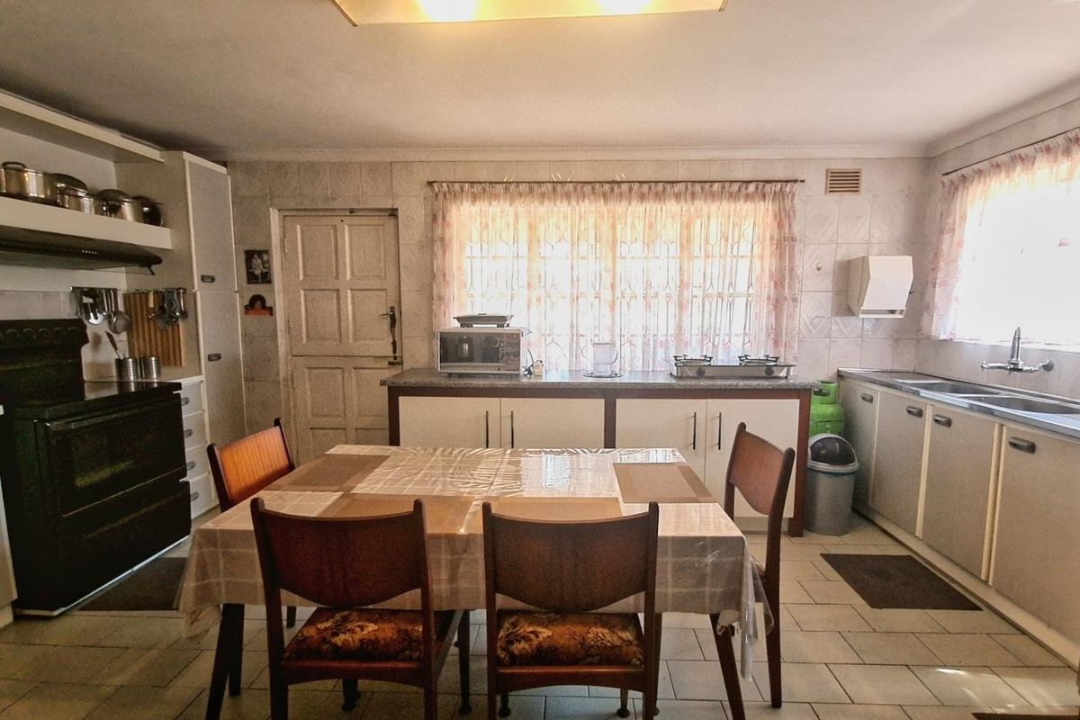 A dated kitchen featuring tiled walls and flooring, built-in cabinetry, and a double sink, offering significant potential for a modern renovation.