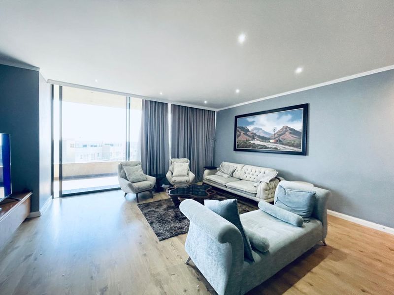 Spacious living room featuring modern laminate flooring, recessed downlighting, and large sliding glass doors providing access to the balcony.