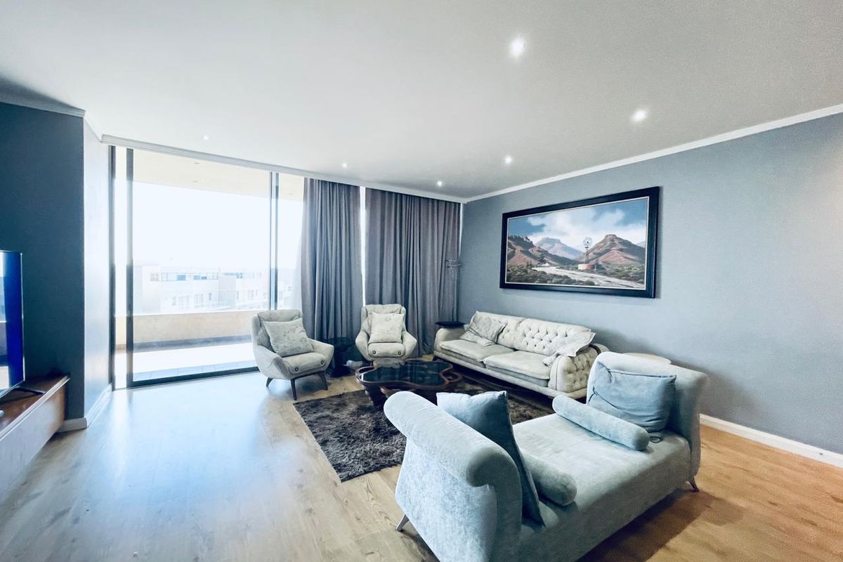 Spacious living room featuring modern laminate flooring, recessed downlighting, and large sliding glass doors providing access to the balcony.