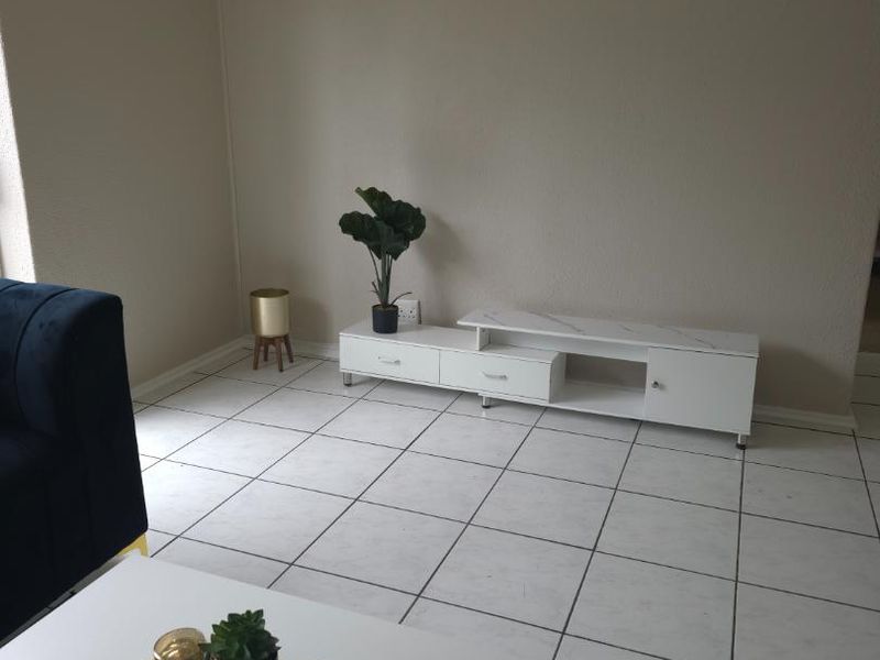 A living room area featuring neutral wall tones and white tiled flooring, providing a clean and simple foundation for interior design.